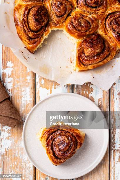 freshly baked cinnamon bun on plate, cinnamon rolls on rustic wooden table viewed from above - sticky bun stock pictures, royalty-free photos & images