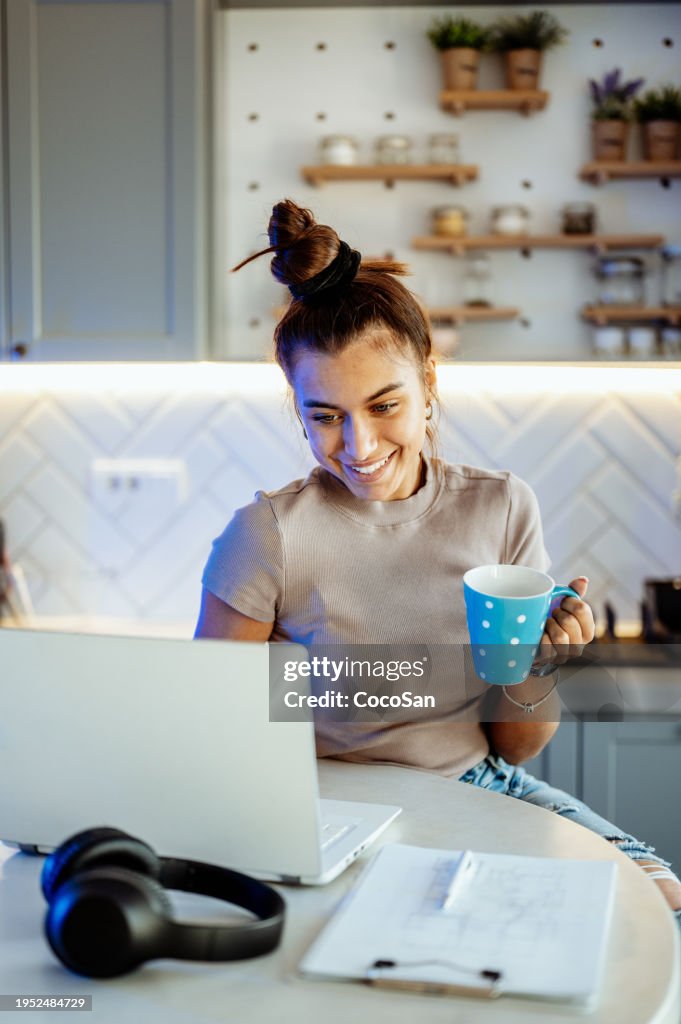 Mujer joven en casa usando computadora portátil y teniendo videollamada