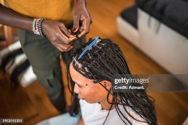 black female hairstylist working on mixed race female client at home - entrançado imagens e fotografias de stock