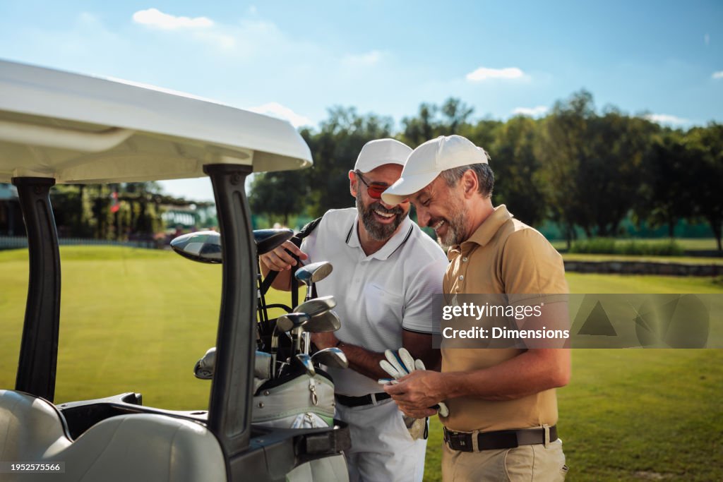 Two friends laughing by the golf cart on the field