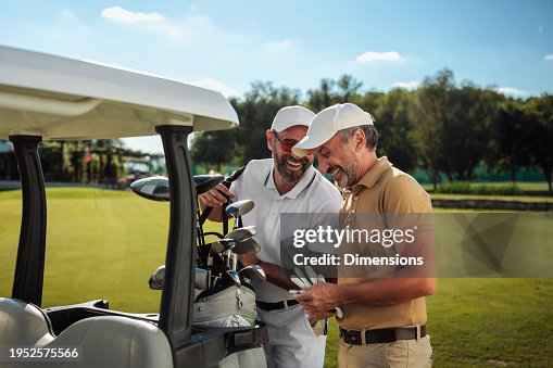 Two friends laughing by the golf cart on the field Two friends laughing by the golf cart on the field