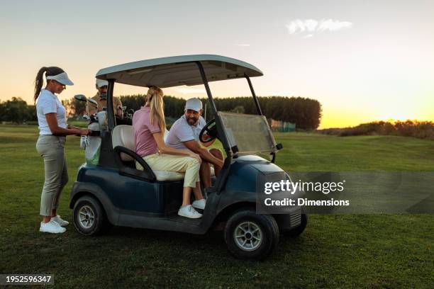 cuatro amigos en una cancha de golf preparándose para montar el carrito de golf - bolsa de golf fotografías e imágenes de stock