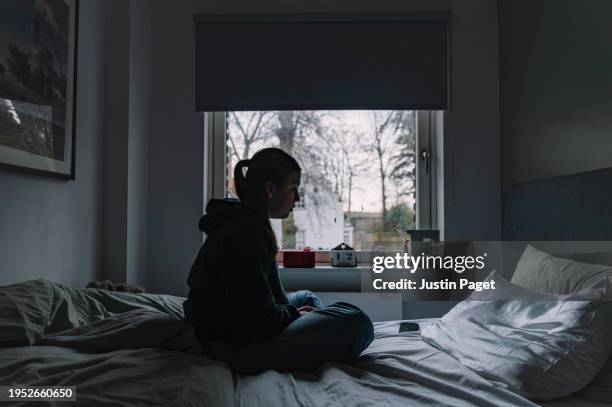 shot of a young woman sitting on her bed - negative emotion - silhouette sitting stock pictures, royalty-free photos & images