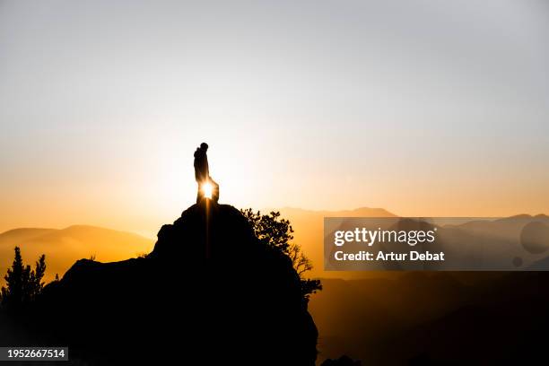 majestic view of a man silhouette on top of a mountain peak with magic golden light. - on top of stock pictures, royalty-free photos & images