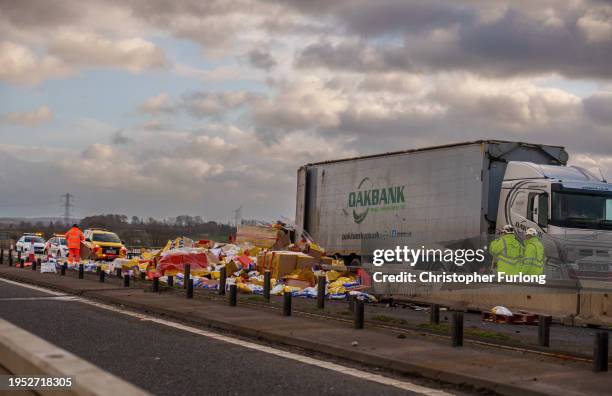 Workers clear up Wotsits and Quavers savoury snacks from the M6 motorway northbound after the wind overturned lorries on the carriageway on January...