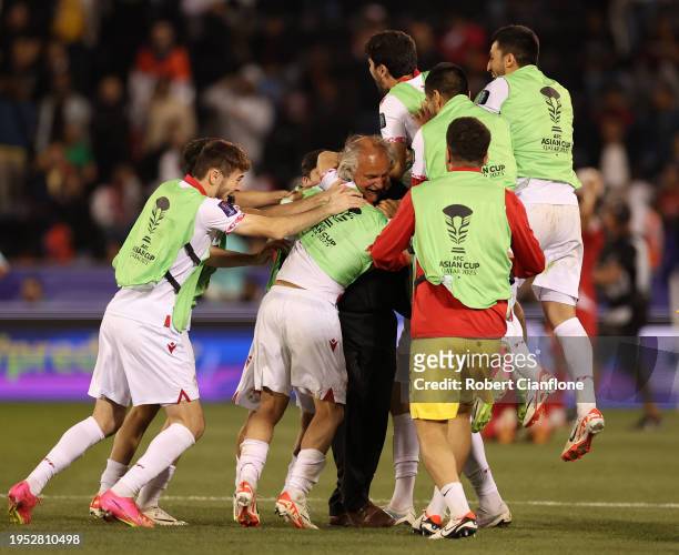 Shahrom Samiev celebrates with Petar Segrt, Head Coach of Tajikistan, and teammates after the team's victory during the AFC Asian Cup Group A match...