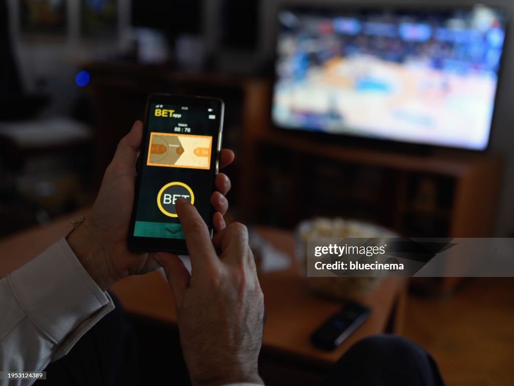 Mature men using smart phone for sports betting.