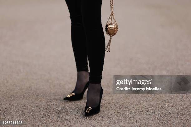 Jurga Fulti seen wearing Vauthier black long catsuit, Etro gold metallic apple shaped mini bag, silver diamond rings and Schiaparelli suede leather...