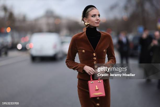 Leonie Hanne seen wearing a brown Schiaparelli outfit, blazer jacket, long skirt, tights, black leather high boots and a red Schiaparelli handbag,...