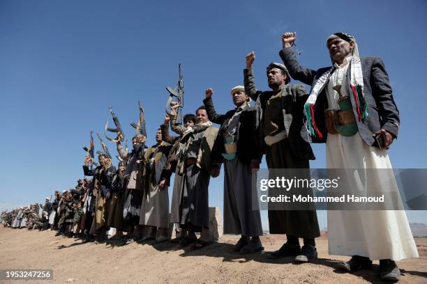 Yemen's Houthi followers lift their rifles and shout slogans as they attend a tribal rally and parade held against the United States-led aerial...