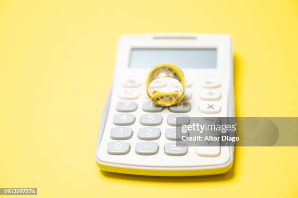 a gold wedding ring on a calculator. costs of a wedding or divorce. - wedding planning stockfoto's en -beelden