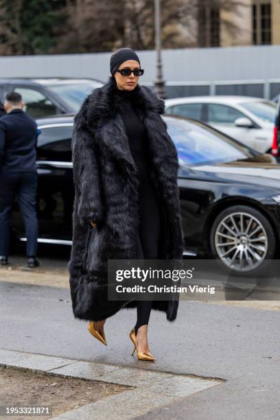 Guest wears black head band, fur coat outside Schiaparelli during the Haute Couture Spring/Summer 2024 as part of Paris Fashion Week on January 22,...