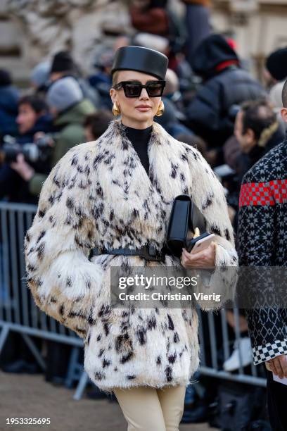 Tatiana Korsakova wears black hat, earrings, animal print white jacket with belt outside Schiaparelli during the Haute Couture Spring/Summer 2024 as...