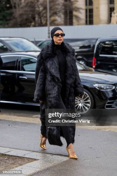 Guest wears black head band, fur coat outside Schiaparelli during the Haute Couture Spring/Summer 2024 as part of Paris Fashion Week on January 22,...