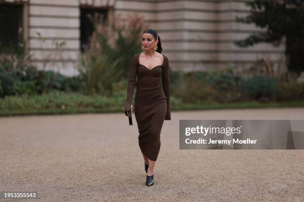 Fashion Week Guest seen wearing a long brown dress, black clutch, black high heels and golden Schiaparelli earrings outside Schiaparelli Show during...