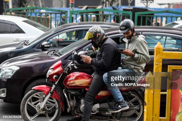 Ridesharing motorbike rider waits for the traffic lights to let him go during a ride with a passenger on a Dhaka street.