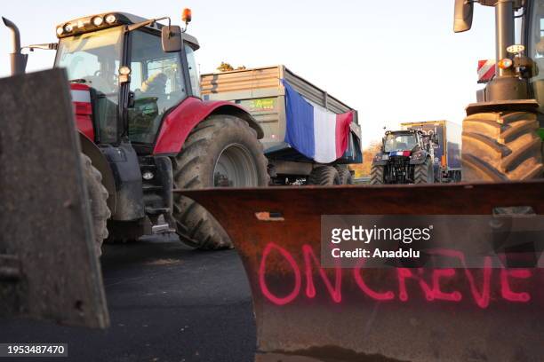 Text spray-painted on the bucket of the tractor is seen as French farmers block the A7 Highway as they protest against taxation and falling incomes...