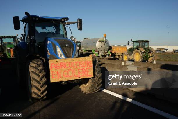 Text spray-painted on the bucket of the tractor is seen as French farmers block the A7 Highway as they protest against taxation and falling incomes...