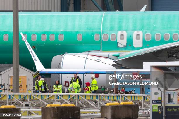 Workers are pictured next to an unpainted 737 aircraft and unattached wing with the Ryanair logo as Boeing's 737 factory teams hold the first day of...