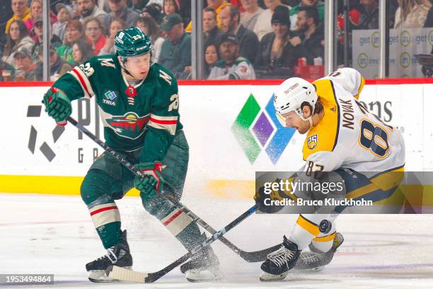 Marco Rossi of the Minnesota Wild and Tommy Novak of the Nashville Predators battle for the puck during the game at the Xcel Energy Center on January...