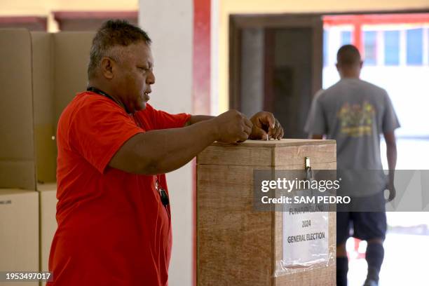 This photo taken on January 25, 2024 shows a man placing his vote into a ballot box at a polling station on election day in Funafuti, the capital of...