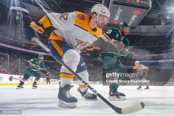 Tommy Novak of the Nashville Predators and Alex Goligoski of the Minnesota Wild skate to the puck during the game at the Xcel Energy Center on...