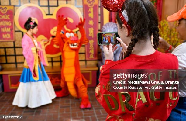 Anaheim, CA Heather Adams dons the new Year of the Dragon spirit jersey as she takes a picture of Mushu and Mulan during Lunar New Year at Disney...