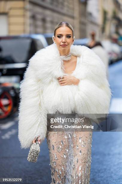 Leonie Hanne wears white faux fur jacket, laced see trough sequined skirt, bag outside Georges Hobeika during the Haute Couture Spring/Summer 2024 as...