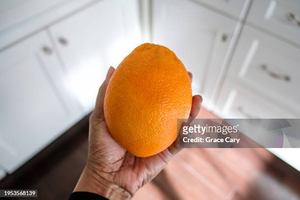 woman holds a navel orange - navel orange stockfoto's en -beelden