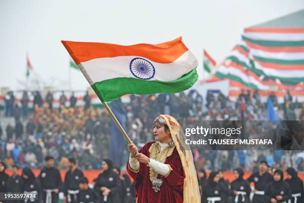 Woman wearing a traditional Kashmiri dress waves the Indian National flag at the Republic Day parade, in Srinagar on January 26, 2024.