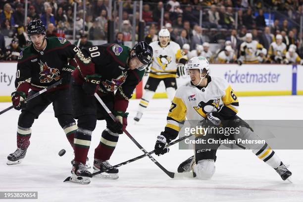 Rickard Rakell of the Pittsburgh Penguins attempts to play the puck against J.J. Moser of the Arizona Coyotes during the first period of the NHL game...