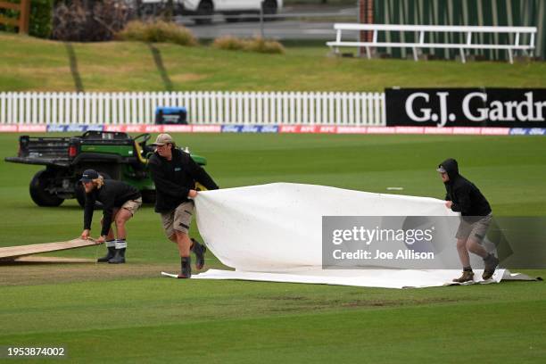 Groundsmen lay covers over the pitch as rain delays play during the T20 Super Smash match between Otago Volts and Northern Districts Brave at...