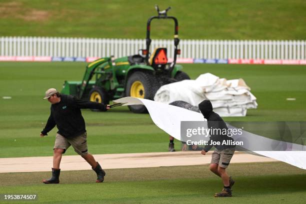 Groundsmen lay covers over the pitch as rain delays play during the T20 Super Smash match between Otago Volts and Northern Districts Brave at...