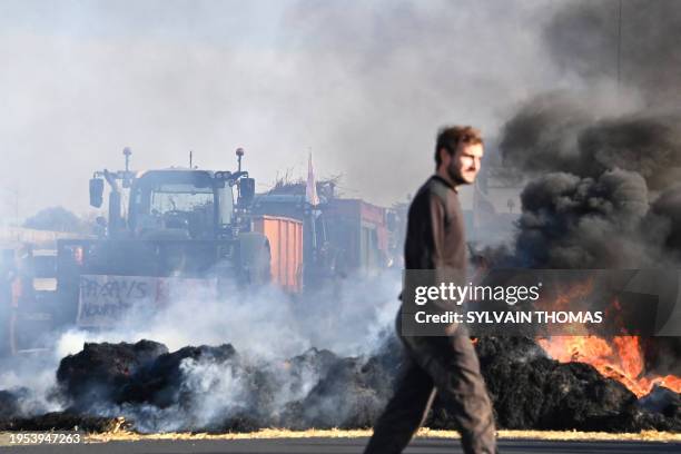 French farmers burn bales of straw as they block the A9 highway during a demonstration called by French farmer unions to protest against a number of...