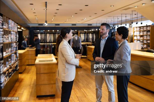 retail clerk helping a couple shopping at a clothing store - retail sales agent stock pictures, royalty-free photos & images