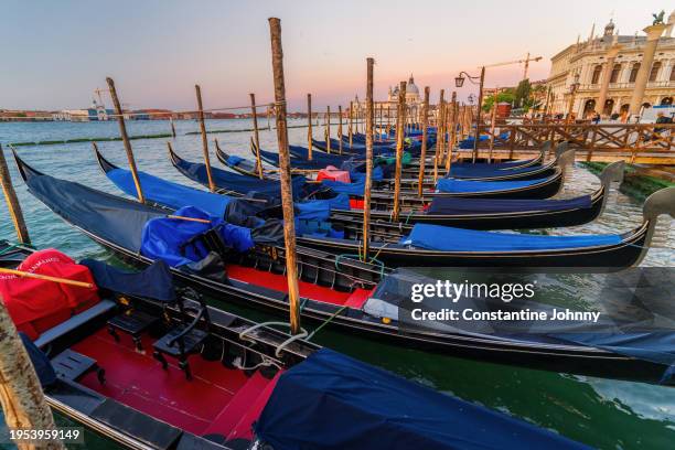 venice waterfront with traditional gondolas at sunrise - gondola traditional boat stockfoto's en -beelden