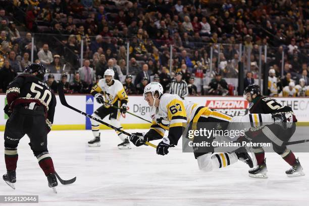 Rickard Rakell of the Pittsburgh Penguins shoots the puck past Sean Durzi of the Arizona Coyotes during the third period of the NHL game at Mullett...