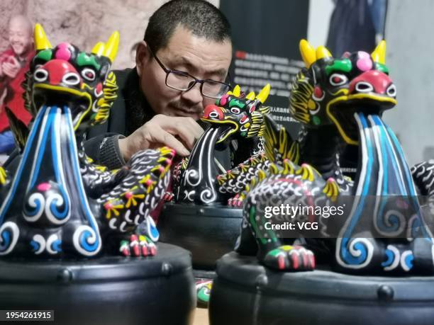 Folk artist colors a dragon-themed 'muddy dog', or ninigou, at an art studio on January 20, 2024 in Zhoukou, Henan Province of China. As the Year of...