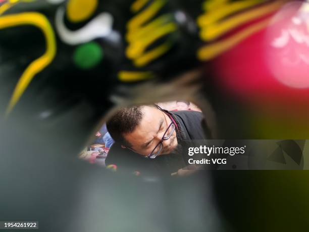 Folk artist colors a dragon-themed 'muddy dog', or ninigou, at an art studio on January 20, 2024 in Zhoukou, Henan Province of China. As the Year of...