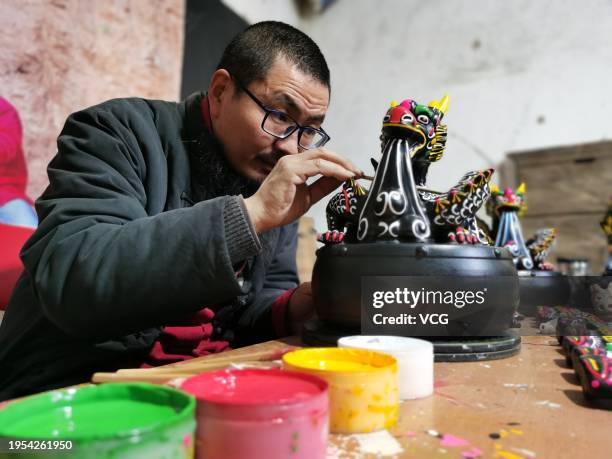 Folk artist colors a dragon-themed 'muddy dog', or ninigou, at an art studio on January 20, 2024 in Zhoukou, Henan Province of China. As the Year of...