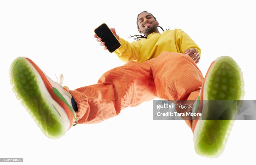 Looking up at man showing camera his mobile phone