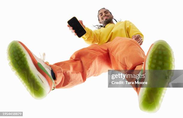 looking up at man showing camera his mobile phone - chaussures noires photos et images de collection