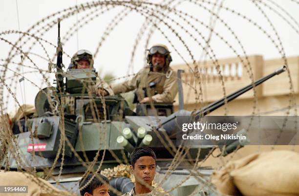 Two Iraqi boys stand between a razorwire protection and a Marines APC April 27, 2003 in Al Kut, Iraq. Two days ago Said Abbas, a Shiite cleric who...