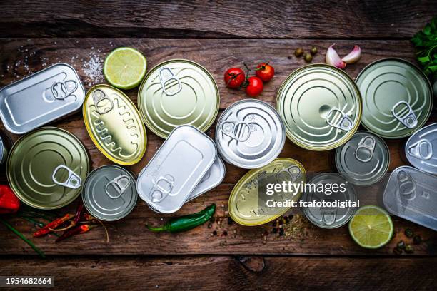 draufsicht auf eine gruppe von konserven, die nebeneinander auf einem holztisch angeordnet sind - lebensmittel in dosen stock-fotos und bilder