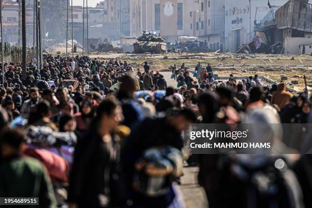 An Israeli tank and other military vehicles guard a position as Palestinians flee Khan Yunis in the southern Gaza Strip on January 26 amid ongoing...
