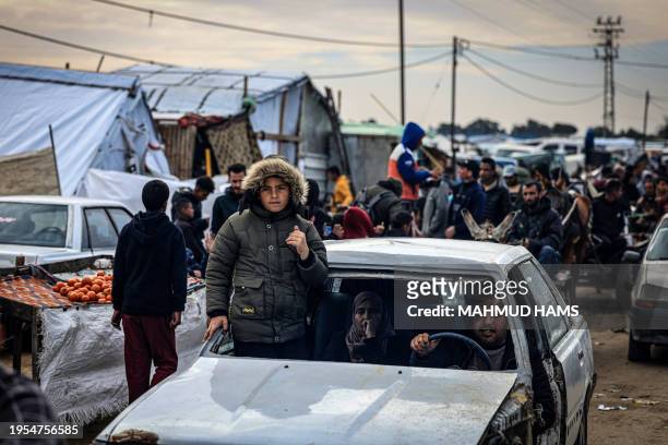 Palestinians use a damaged vehicle as they flee Khan Yunis in the southern Gaza Strip on January 26 amid ongoing battles between Israel and the...