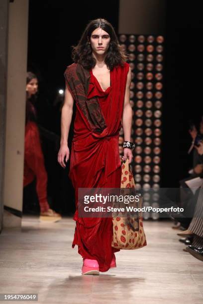 Model walks the runway at the Vivienne Westwood show during Paris Fashion Week Autumn/Winter 2016/17, he wears a long red velvet gown, draped around...