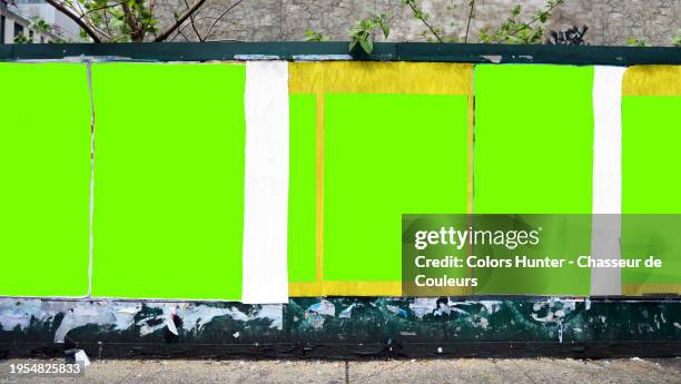 six green backgrounds with irregular contours and different formats on a wall in manhattan, new york city, united states. tree branches and leaves. dirty sidewalk. sunlight. natural colors. no logo or trademark. no graffiti or street art. - poster wall stock-fotos und bilder