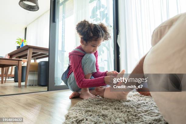 close up shot of elementary-aged daughter with casual clothing wrapping the ankle of the unrecognized father using elastic bandage for taking care of her father foot and ankle showing healthcare in a family. - ace bandage stock pictures, royalty-free photos & images