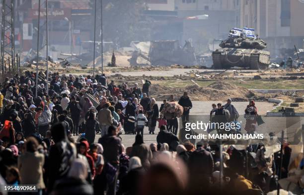 An Israeli tank takes position at the western entrance of Khan Yunis'refugee camp as Palestinians flee with a few belongings to safer areas further...